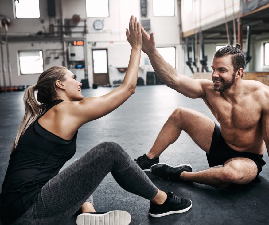 Två personer ger varandra high five efter avslutat träningspass i gymmiljö